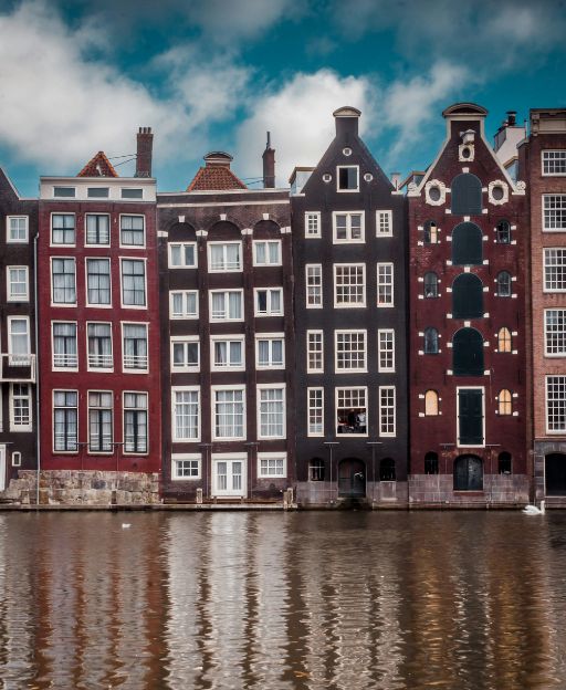 Amsterdam Golden Age canal houses reflected in water — tall narrow merchant buildings with step gable facades