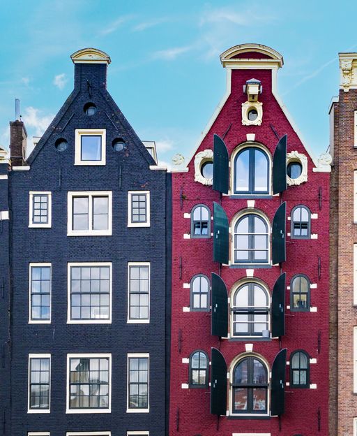 Damrak canal houses of Amsterdam with tall windows reflecting the Dutch open-curtain tradition