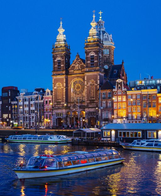 Basilica of Saint Nicholas in Amsterdam lit up at night, reflected in the canal