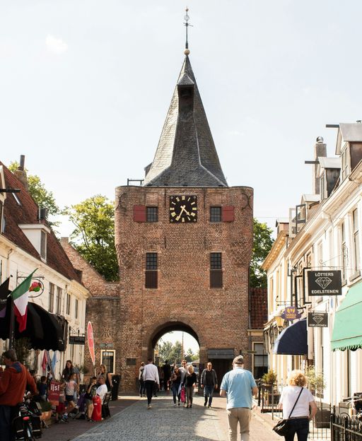 The Vischpoort medieval gate tower in Elburg, the Netherlands, with pedestrians walking beneath on a sunny day