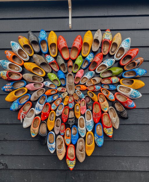 Colourful painted Dutch wooden clogs arranged in a heart shape on a dark wall, Netherlands