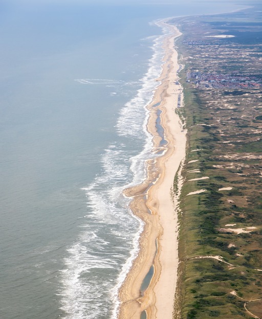 Aerial view of Dutch North Sea coastline with golden sand dunes and breaking waves