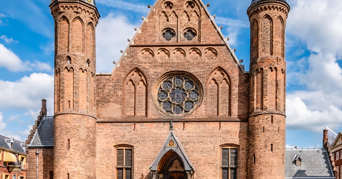 Red brick Gothic church facade with twin towers and rose window
